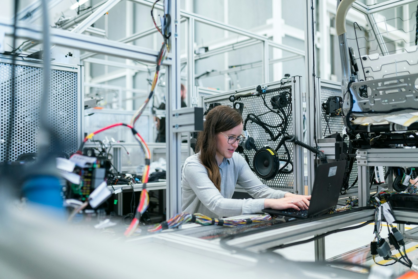Engineer working at a laptop beside manufacturing equipment on a clean factory floor